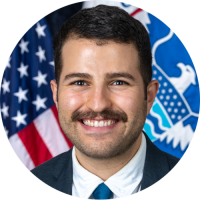 Jeremy headshot in a suit with United States of America flags in the background